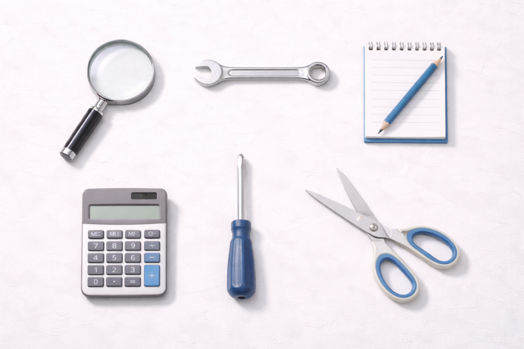 A neatly arranged flat lay shows common tools and office items including a magnifying glass, wrench, calculator, screwdriver, scissors, and a notepad with a pencil.